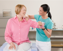 Caregiver assisting female elder in excercise